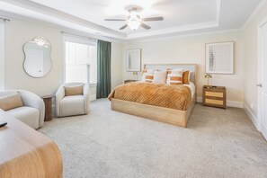 Ein Schlafzimmer mit Bett, Sessel, Nachttisch, Spiegel und Deckenventilator.