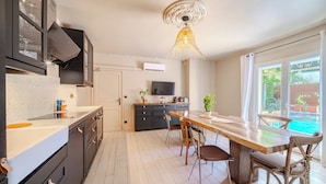 A modern kitchen with a dining area, a TV, and a large window with a view. - 12345677890 (Montpellier)