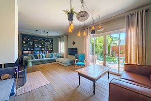 Un salon comprenant un canapé, un fauteuil, une table basse et une bibliothèque.