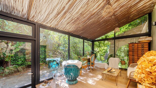 A conservatory with glass walls, wooden flooring, and a variety of decorative items. - 12345677890 (Montpellier)