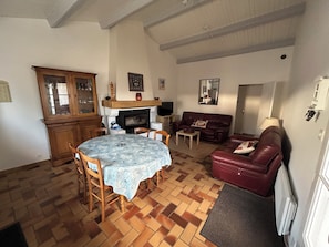Ein Wohnzimmer mit Kamin, Esstisch und einem roten Ledersofa.