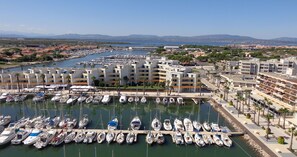 A marina with numerous boats docked, surrounded by multi-story buildings with balconies. - BRIGHT STUDIO WITH TERRACE FACING THE SEA AND MARINA (Le Barcarès)