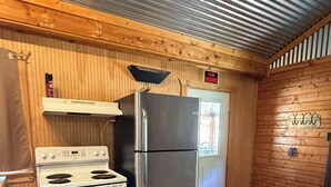A kitchen with a stove, refrigerator, and wooden walls.