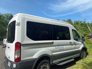 Ein weißer Van mit 'InnSeason Resorts' Schriftzug, geparkt an einer Straße, im Hintergrund Grünpflanzen.