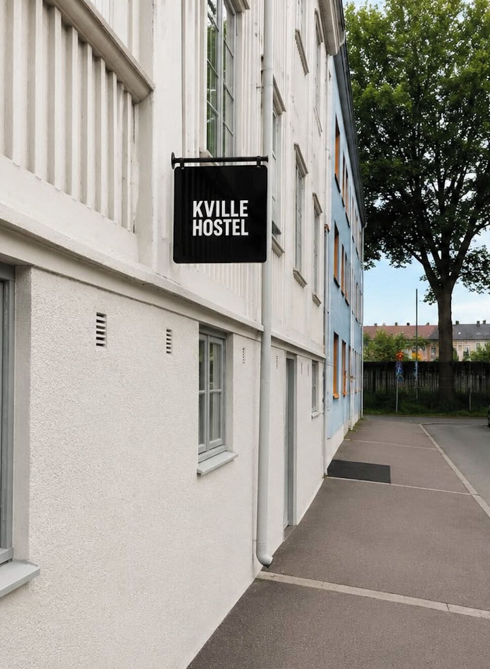 Une auberge de jeunesse appelée « KVILLE HOSTEL », avec une façade blanche et une fenêtre bien visible.