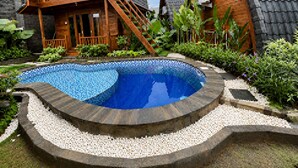 Una casa de madera con balcón, piscina y jardín.