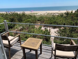 Une terrasse avec une table et des chaises donnant sur une plage.