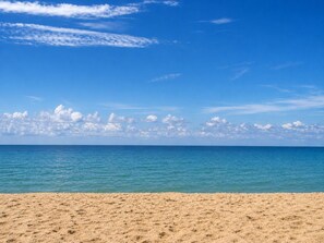 Een strand met helderblauw water en een zandstrand.