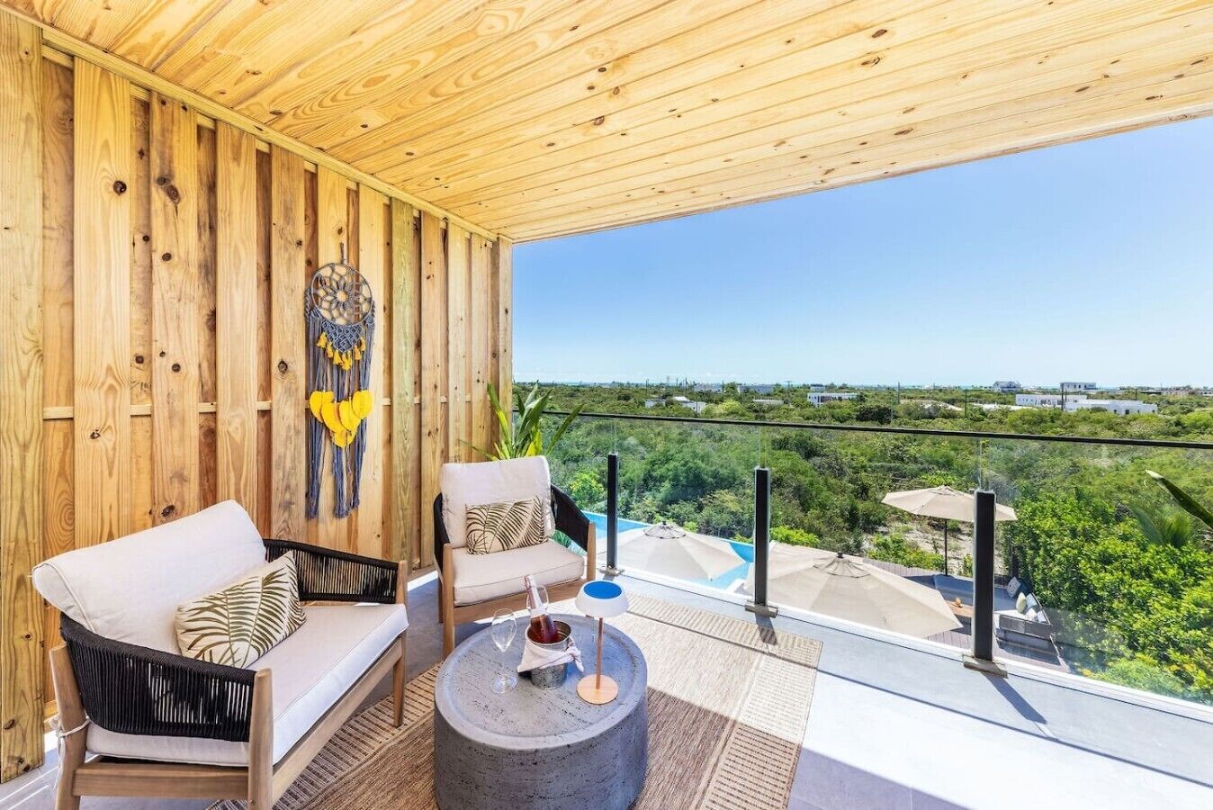 Un balcón con paredes de madera, vistas a zonas verdes y una piscina.