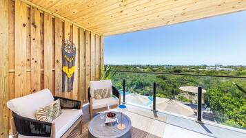 Un balcón con paredes de madera, vistas a zonas verdes y una piscina.
