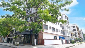 A multi-story residential building with a white facade, balconies, and a tree in front. - Classic Newtown Bus Stand (Barasat)