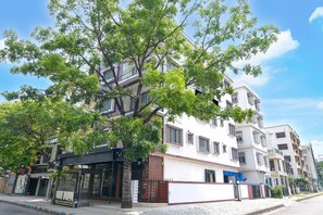A multi-story residential building with a white facade, balconies, and a tree in front. - Classic Newtown Bus Stand (Barasat)