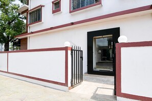 A building with a gated entrance, a black door, and a window with a metal grill. - Classic Newtown Bus Stand (Barasat)