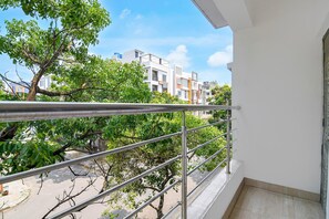A balcony with a metal railing overlooking a residential area with trees and buildings. - Classic Newtown Bus Stand (Barasat)