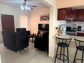 A living room with a TV, black sofas, a coffee table, and a ceiling fan. - Family house with swimming pool 5 minutes from shopping centers, San Miguel (San José Quelepa)