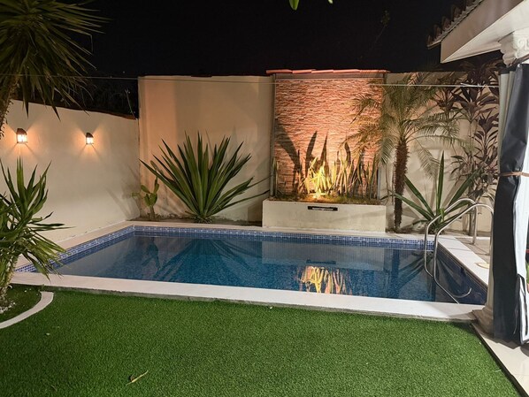 A swimming pool with artificial grass, a stone wall, and various plants. - Family house with swimming pool 5 minutes from shopping centers, San Miguel (San José Quelepa)