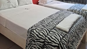 Habitación de hotel con dos camas, pared roja, ventana con cortinas y un escritorio con una silla.