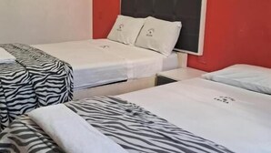 Una habitación de hotel con dos camas individuales, una pared de acento roja y una colcha con estampado de cebra.
