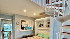 Un dormitorio con cama, una escalera, una zona de cocina y vistas al exterior.