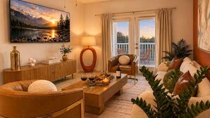 Uma sala de estar com sofá, mesa de centro, luminária, quadro e vista para o exterior.