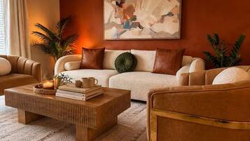 Ein Wohnzimmer mit einer Couch, Sesseln, einem Couchtisch und einem Bild an der Wand.