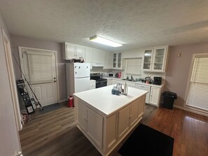 A kitchen with white cabinets, a refrigerator, a stove, and a microwave.