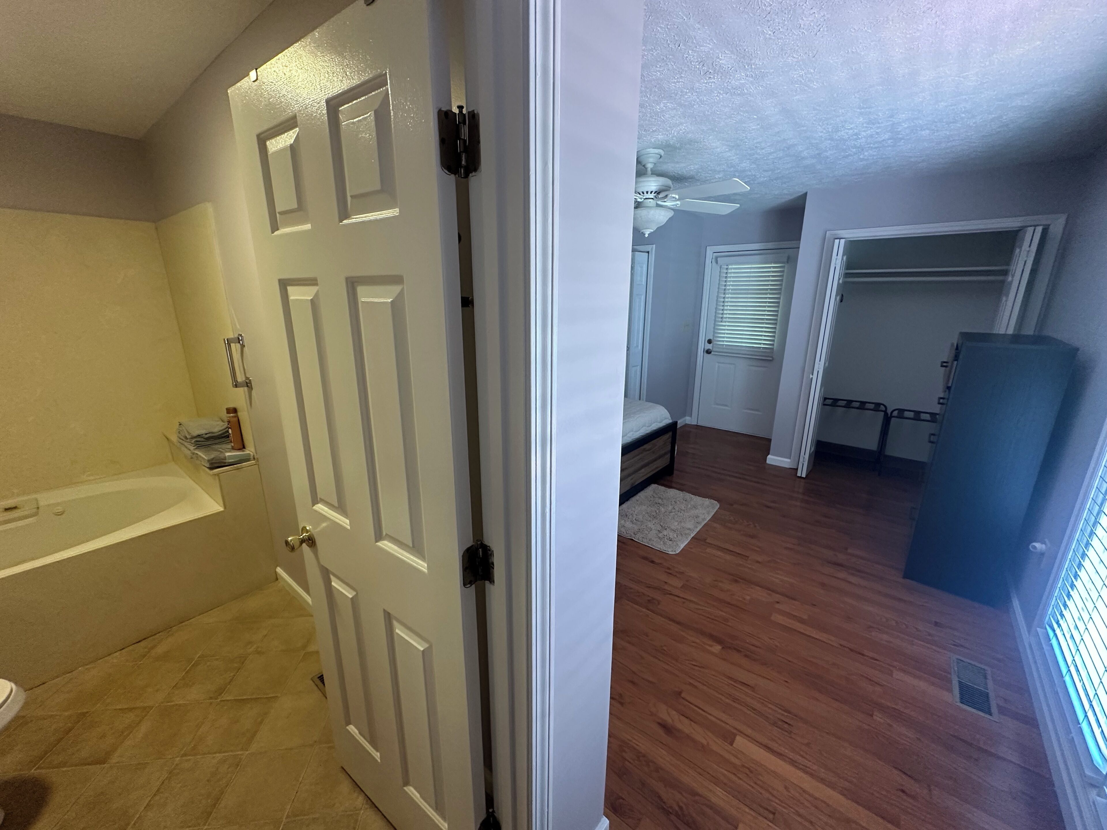 Una camera da letto con un letto, una ventola a soffitto e una finestra con persiane.