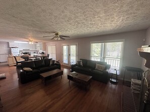 A spacious living room with a ceiling fan, a dining area, and a kitchen in the background.