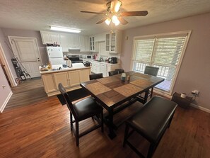 A kitchen with white cabinets, a dining table with black chairs, and a ceiling fan.