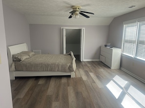 A bedroom with a bed, dresser, and ceiling fan. - The Lakehouse at Antioch on West Point Lake (LaGrange)