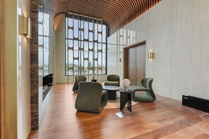 Eine moderne Lobby mit gewölbter Decke, großen Fenstern und einer Sitzecke mit Sofas und einem Couchtisch.