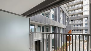 Monikerroksinen rakennus, jossa on parvekkeita, metallikaiteet ja näkymä alapuolella olevalle kadulle.