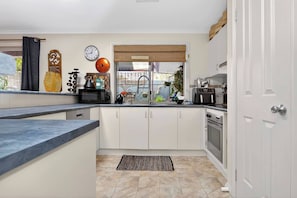 A kitchen with white cabinets, a microwave, a kettle, and a toaster. - The Sellicks Atelier Beachside Vintage Retreat (Sellicks Beach)