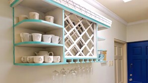 A kitchen with teal shelves holding white cups and glasses, a blue door, and a white lattice window. - Chic casual ocean themed condo located  in Tobago 's most exclusive compound . (Lowlands)