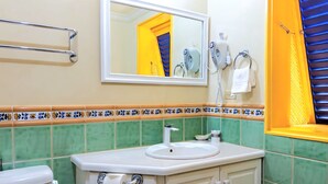 A bathroom with a toilet, sink, mirror, towel rack, and hairdryer. - Chic casual ocean themed condo located  in Tobago 's most exclusive compound . (Lowlands)