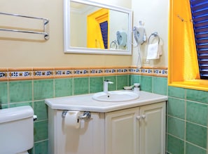 A bathroom with a toilet, sink, mirror, towel rack, and hairdryer.