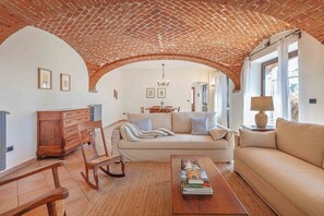 A living room with a brick ceiling, a sofa, a coffee table, and a wooden rocking chair.
