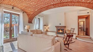 Una sala de estar con techo de ladrillo, chimenea, sofá y comedor.