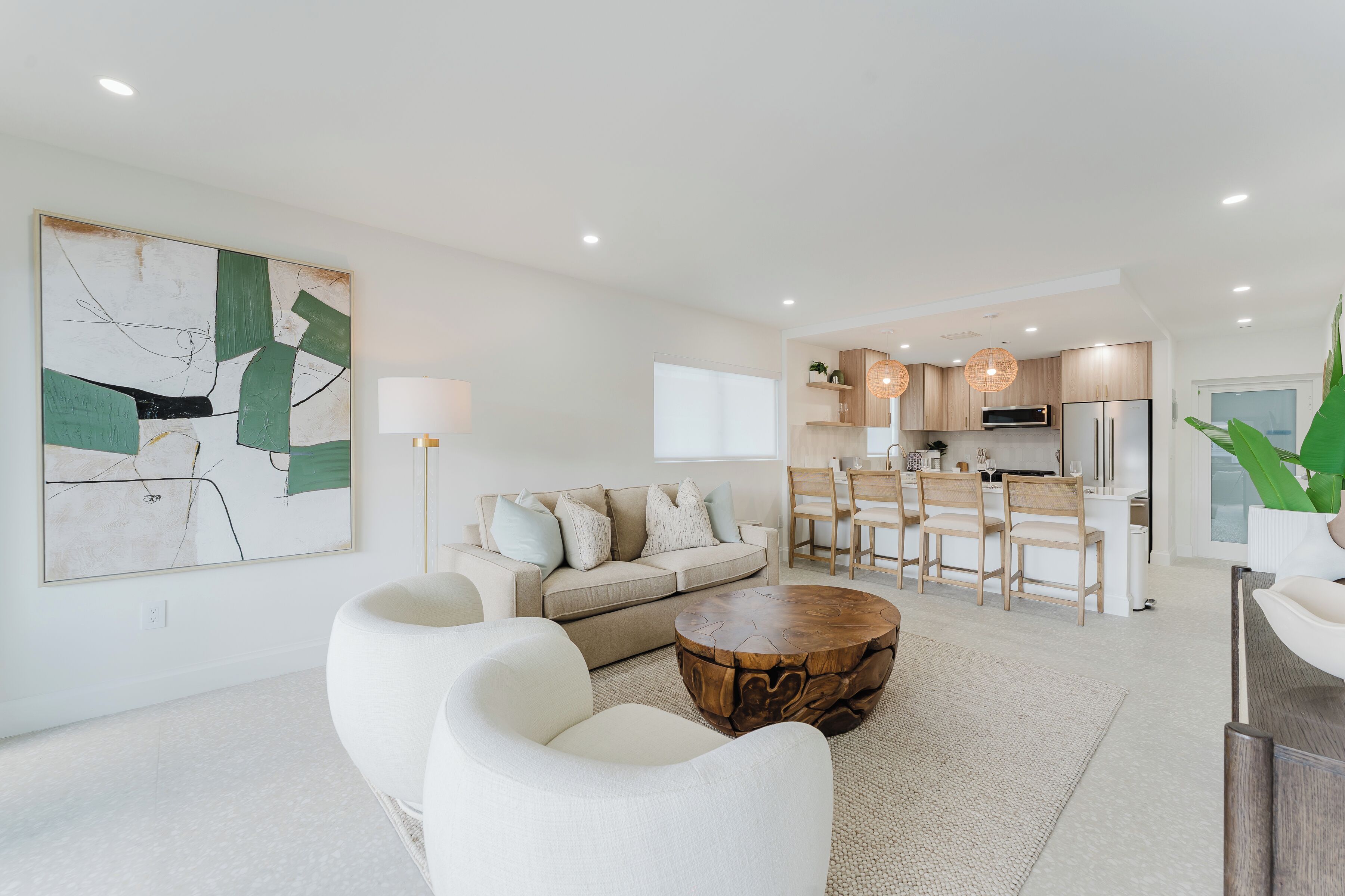 A modern living room with a sofa, chairs, a coffee table, and a kitchen in the background.