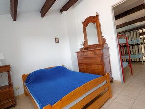 Ein Schlafzimmer mit einem hölzernen Bett, einem Schminktisch, einem Spiegel und einer roten Leiter.