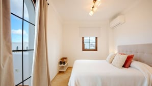 Une chambre à coucher avec un lit, une table de chevet, une fenêtre et un luminaire au plafond.
