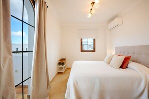 Ein Schlafzimmer mit einem Bett, einem Nachttisch, einem Fenster und einer Deckenleuchte.