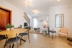 A modern living room with a dining table, chairs, a sofa, a TV, a staircase, and a large window. - Villa in Lanzarote (Yaiza) | Chillout Garden | 3BR (Yaiza)