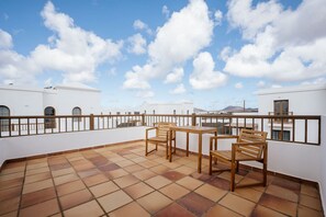 Une terrasse sur le toit, dotée d’un sol carrelé, d’une table en bois et de deux chaises.