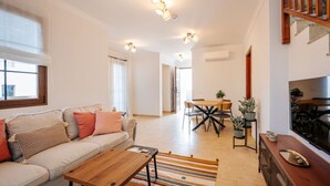 Un salon moderne comprenant un canapé, une table basse, une table à manger et un téléviseur.