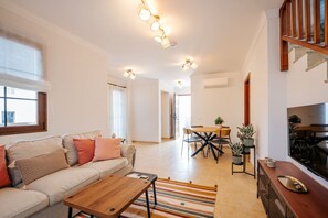 Ein modernes Wohnzimmer mit Sofa, Couchtisch, Esstisch und Fernseher.