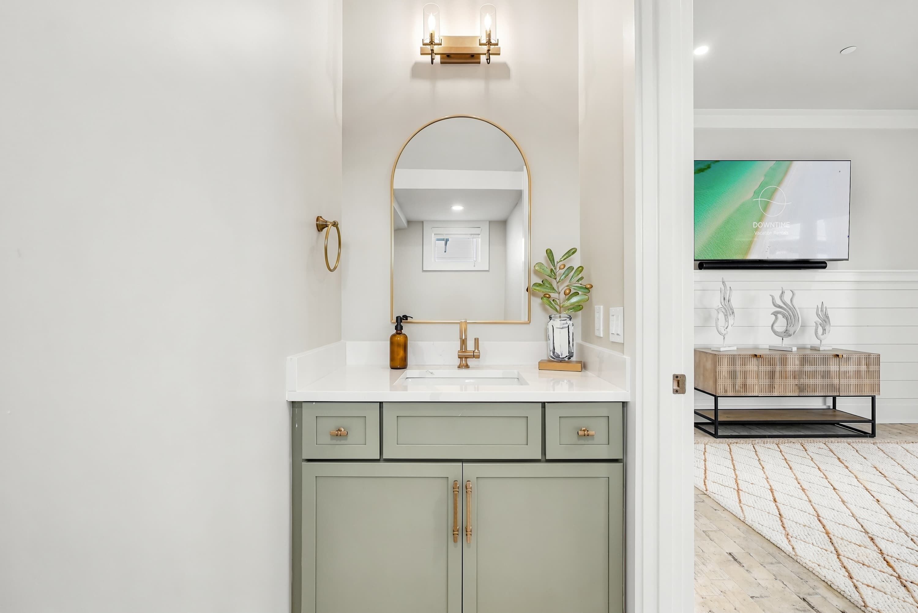 A modern bathroom with a large mirror, a sink, and a television mounted on the wall.