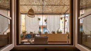 A balcony with wicker furniture, hanging plants, and a thatched ceiling.