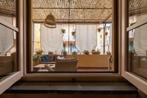 Un balcon agrémenté de meubles en osier, de plantes suspendues et d’un plafond en chaume.