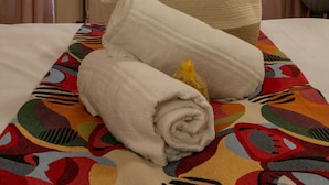 A hotel room with a bed, a window with curtains, a colorful rug, and a chair.